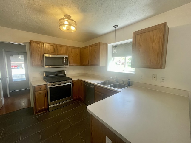 kitchen with stainless steel appliances, a sink, light countertops, a peninsula, and a textured ceiling