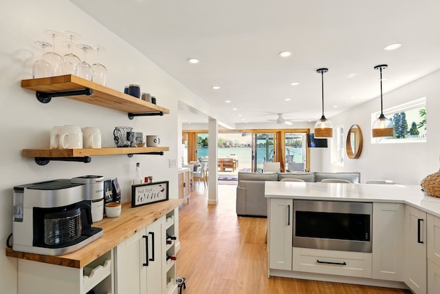 kitchen featuring open shelves, stainless steel microwave, recessed lighting, butcher block countertops, and light wood-style floors