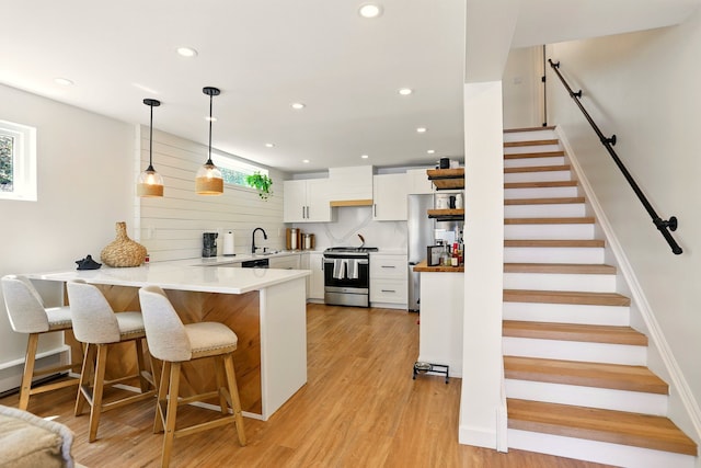 kitchen with appliances with stainless steel finishes, a peninsula, a sink, white cabinets, and a kitchen bar