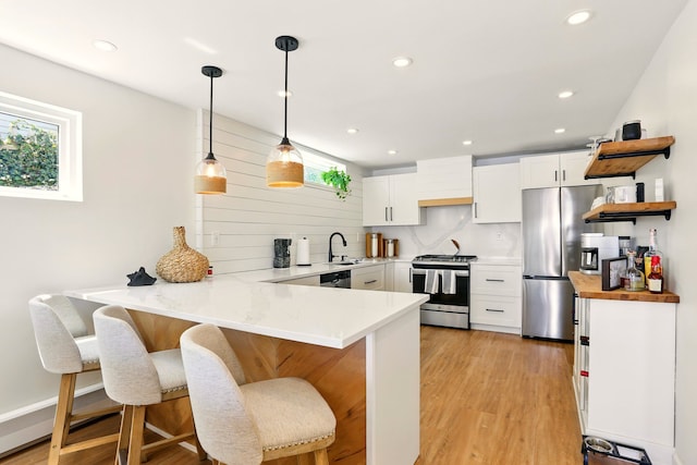 kitchen featuring stainless steel appliances, a peninsula, a sink, plenty of natural light, and recessed lighting