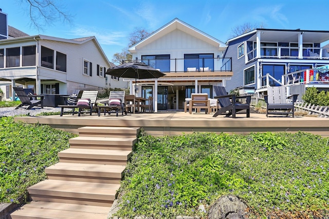 back of house featuring board and batten siding, a balcony, and a wooden deck