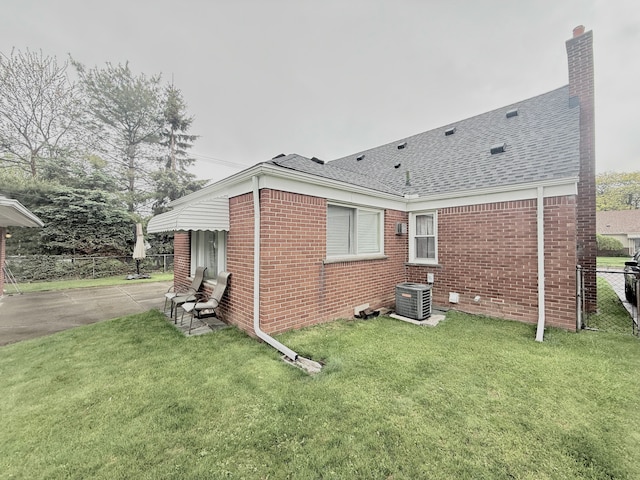 view of home's exterior featuring cooling unit, brick siding, a shingled roof, and a chimney