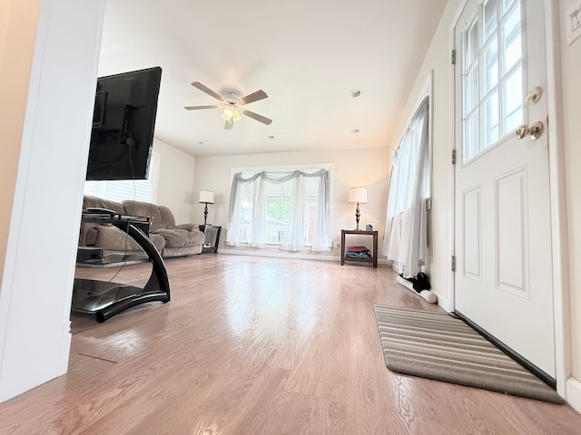 living area with wood finished floors, a ceiling fan, and baseboards