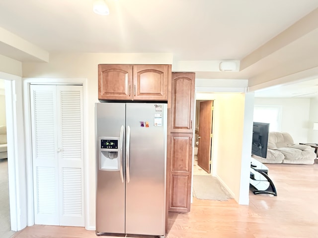 kitchen with stainless steel refrigerator with ice dispenser, light wood-style floors, and open floor plan