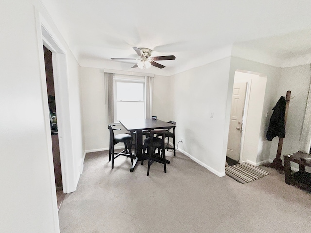 dining room featuring baseboards, a ceiling fan, and light carpet