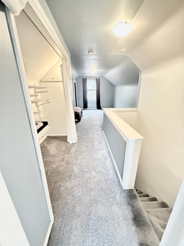 corridor featuring lofted ceiling, carpet, and an upstairs landing