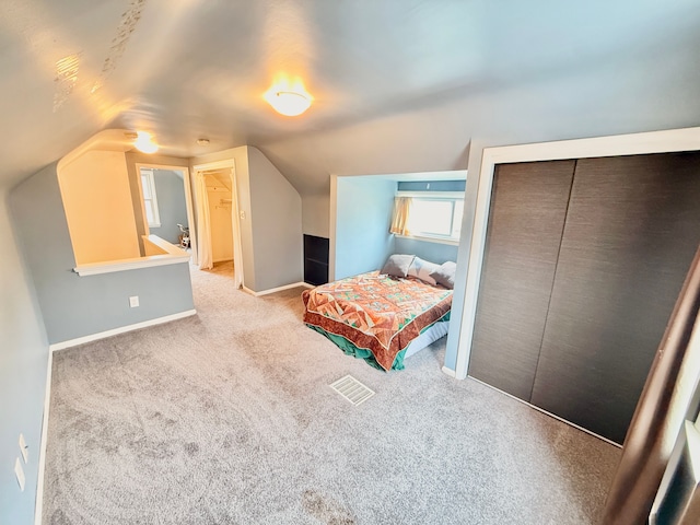 carpeted bedroom featuring baseboards, vaulted ceiling, and a closet