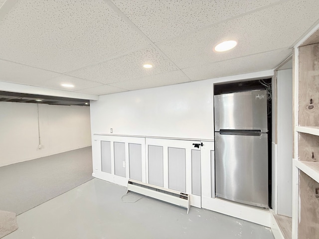 finished below grade area featuring freestanding refrigerator, baseboard heating, and recessed lighting