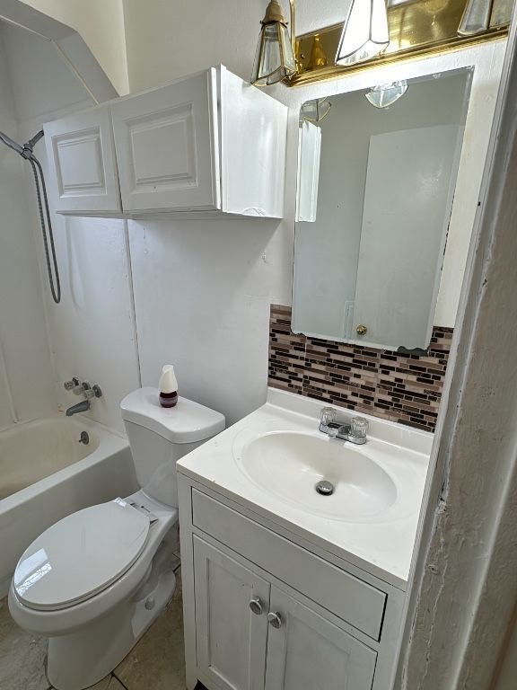 full bathroom featuring toilet, decorative backsplash, vanity, and shower / washtub combination