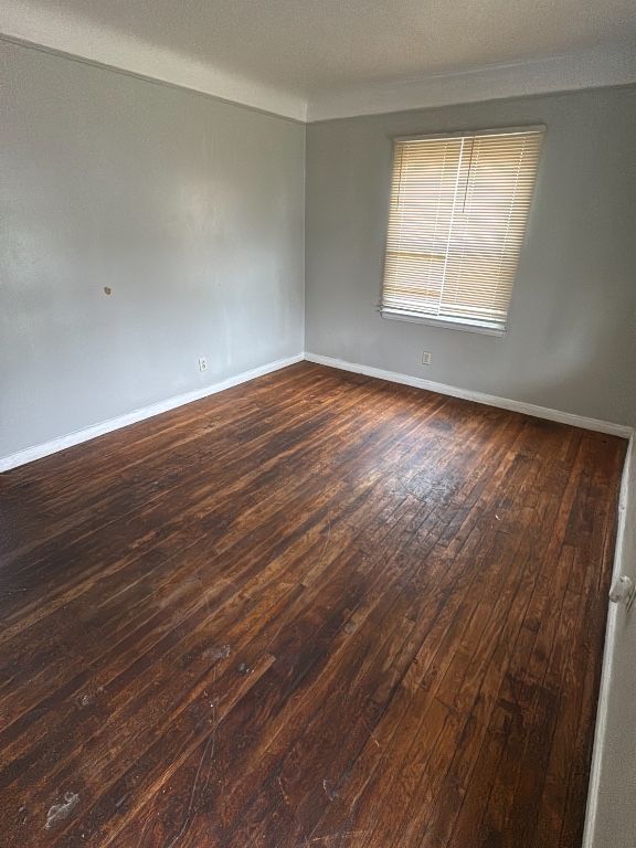 unfurnished room featuring dark wood-style flooring and baseboards