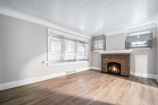 20410 Hull St, Highland Park, MI 48203 - unfurnished living room with wood finished floors, a textured ceiling, a stone fireplace, and baseboards