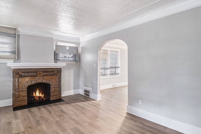 20410 Hull St, Highland Park, MI 48203 - unfurnished living room featuring a textured ceiling, baseboards, wood finished floors, a fireplace, and arched walkways