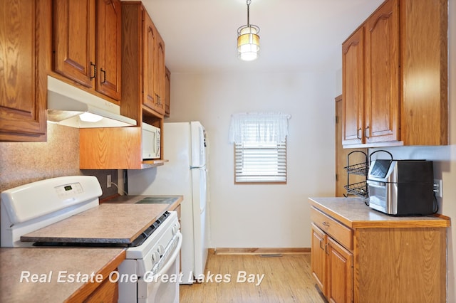 2505 Blake St, Saginaw, MI 48602 - kitchen with white appliances, under cabinet range hood, light wood finished floors, and brown cabinets