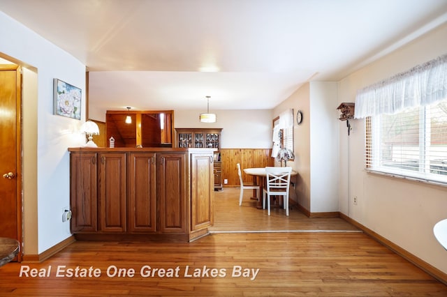 2505 Blake St, Saginaw, MI 48602 - kitchen featuring light wood-style flooring, wainscoting, baseboards, wooden walls, and decorative light fixtures