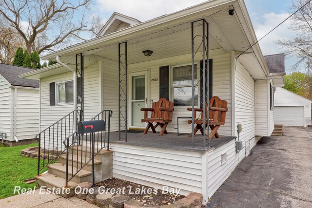2505 Blake St, Saginaw, MI 48602 - view of front of property with covered porch, an outdoor structure, a detached garage, and a shingled roof