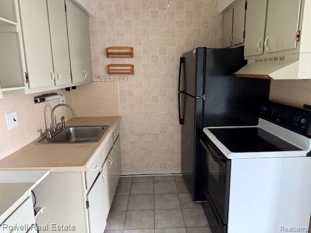 17121 Redford St Unit 212, Detroit, MI 48219 - kitchen with range with electric stovetop, under cabinet range hood, a sink, light tile patterned flooring, and light countertops