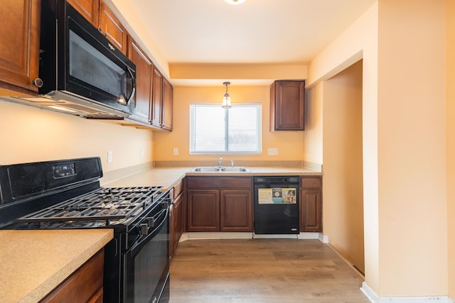 4770 Matthew St, Westland, MI 48186 - kitchen with black appliances, a sink, light wood-style floors, light countertops, and decorative light fixtures