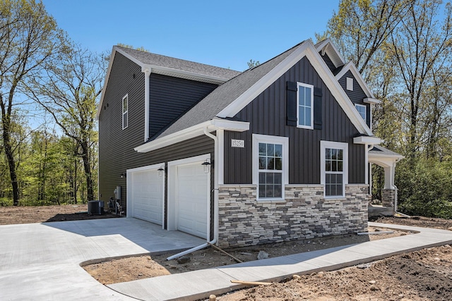 15250 Alister Mackenzie Ave, Augusta, MI 49012 - view of side of property featuring driveway, stone siding, a shingled roof, board and batten siding, and central air condition unit