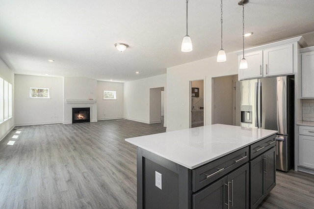 15250 Alister Mackenzie Ave, Augusta, MI 49012 - kitchen featuring stainless steel fridge, a kitchen island, wood finished floors, light countertops, and a glass covered fireplace