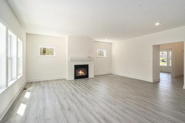 15250 Alister Mackenzie Ave, Augusta, MI 49012 - unfurnished living room with light wood-style floors, a glass covered fireplace, recessed lighting, and baseboards