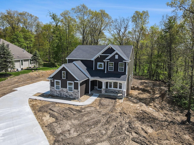 15250 Alister Mackenzie Ave, Augusta, MI 49012 - view of front of house featuring stone siding, concrete driveway, covered porch, and roof with shingles