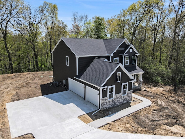 15250 Alister Mackenzie Ave, Augusta, MI 49012 - view of home's exterior with stone siding, concrete driveway, board and batten siding, roof with shingles, and an attached garage