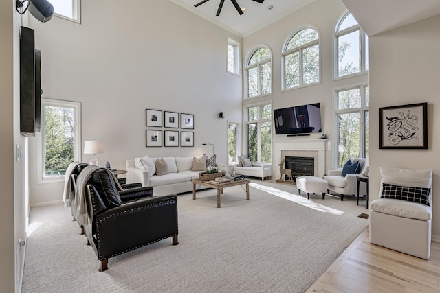 26930 Victory Ct, South Lyon, MI 48178 - living area with a high ceiling, plenty of natural light, a glass covered fireplace, ceiling fan, and crown molding