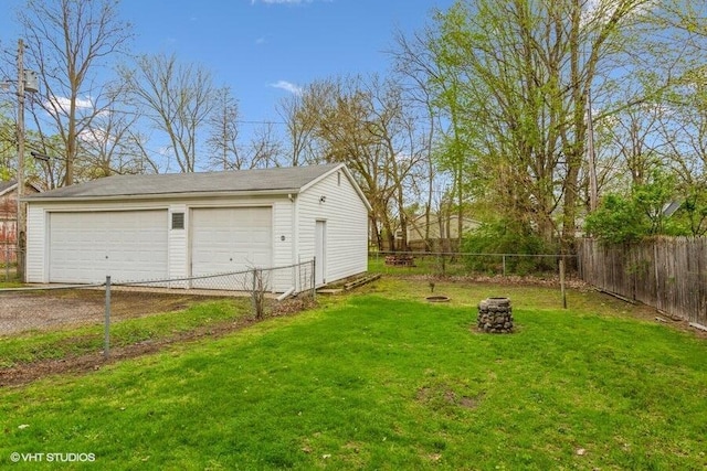 view of yard featuring a detached garage, an outdoor structure, and a fire pit