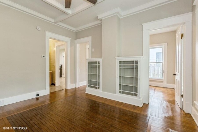 spare room with wood finished floors, baseboards, ornamental molding, beamed ceiling, and a ceiling fan