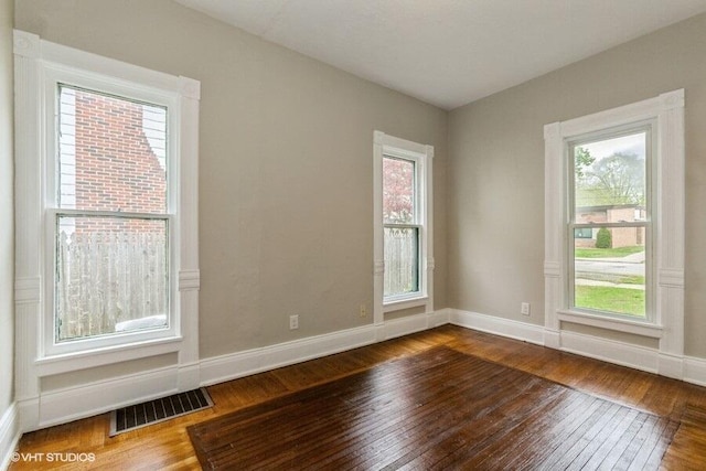 unfurnished room with dark wood-style floors and healthy amount of natural light