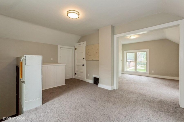 carpeted spare room featuring vaulted ceiling and baseboards