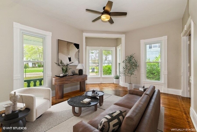 living area with healthy amount of natural light, ceiling fan, wood finished floors, and baseboards