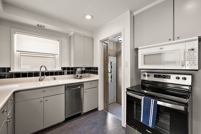 kitchen featuring appliances with stainless steel finishes, a sink, tasteful backsplash, recessed lighting, and light countertops