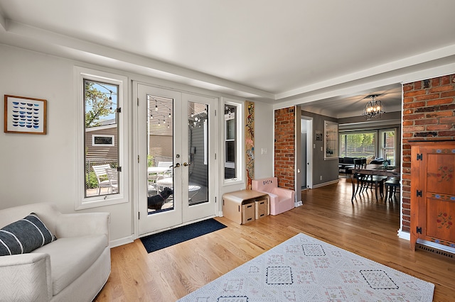 doorway with wood finished floors, french doors, a chandelier, and baseboards
