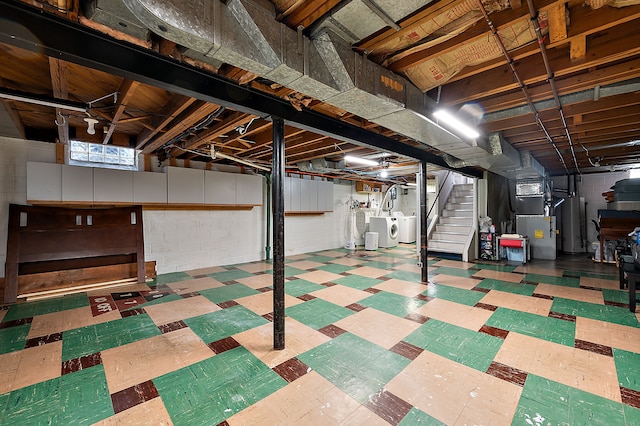 below grade area featuring tile patterned floors, washer and dryer, stairway, heating unit, and concrete block wall