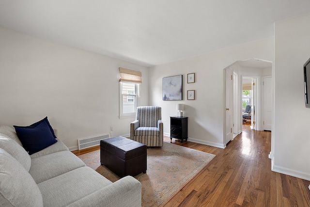 living area with arched walkways, wood finished floors, and baseboards