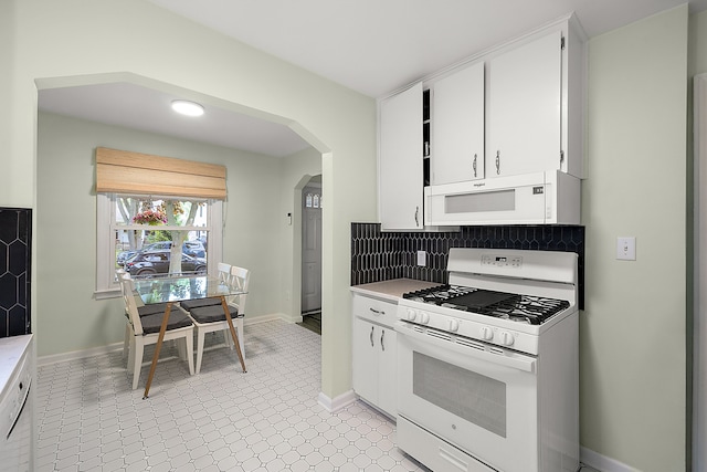 kitchen featuring white appliances, arched walkways, light countertops, and white cabinets