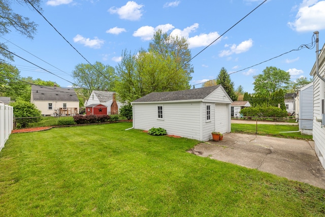 view of yard with an outdoor structure, a detached garage, a patio, and concrete driveway