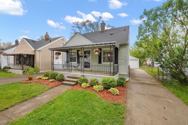 bungalow-style home with covered porch, a front lawn, an outbuilding, a garage, and a chimney
