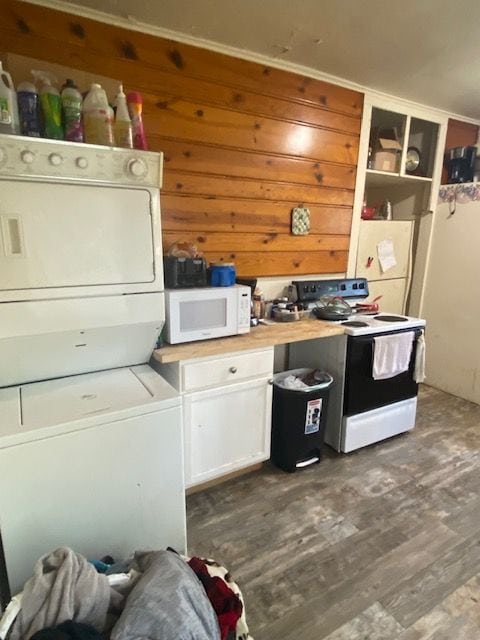 437 W Mount Morris St, Mount Morris, MI 48458 - kitchen with white appliances, estacked washer and dryer, white cabinetry, dark wood-style flooring, and wood walls