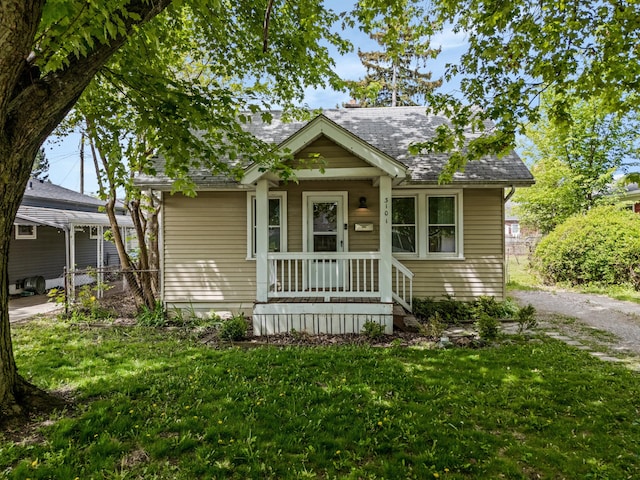 bungalow-style house featuring a front lawn and roof with shingles
