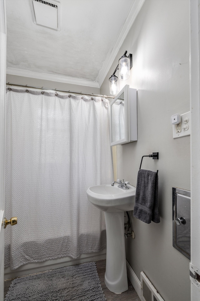 full bath featuring crown molding, shower / bathtub combination with curtain, wood finished floors, and a sink