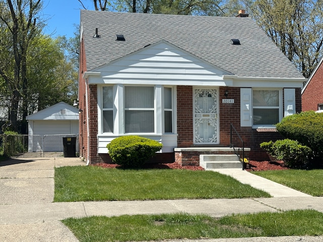 bungalow-style house with roof with shingles, a garage, brick siding, and an outdoor structure