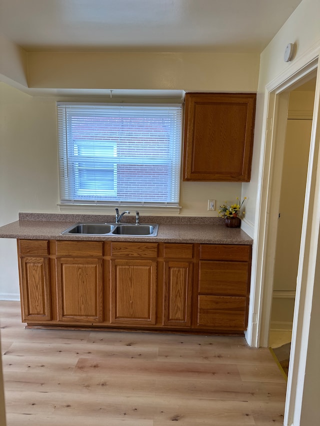 kitchen featuring a sink, brown cabinetry, and light wood finished floors