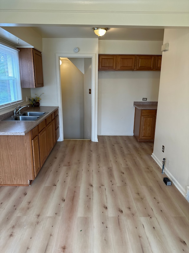 kitchen featuring a sink, brown cabinets, and light wood-type flooring