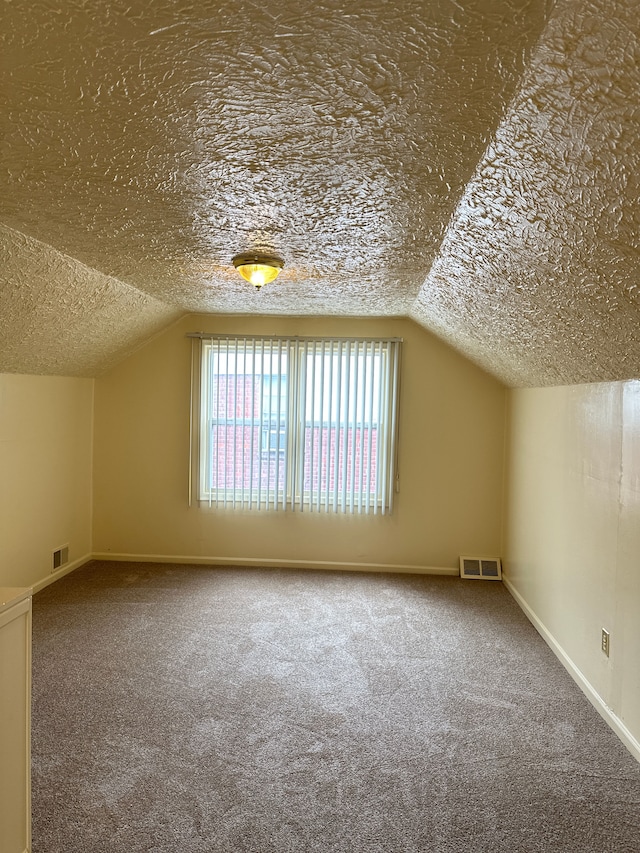 bonus room featuring vaulted ceiling, carpet flooring, baseboards, and a textured ceiling