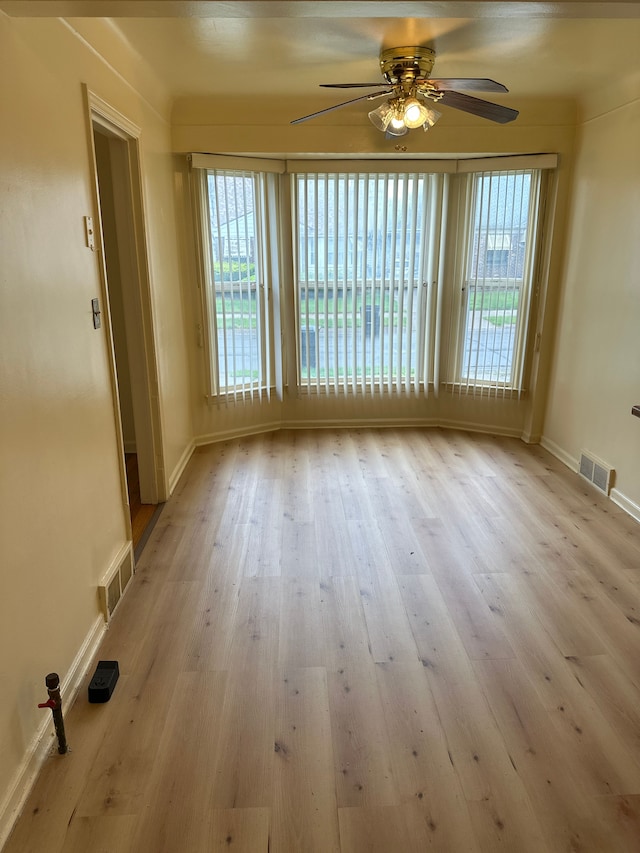 unfurnished room with a ceiling fan, plenty of natural light, and wood finished floors
