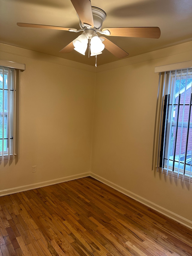 empty room featuring dark wood-style flooring, ceiling fan, and baseboards