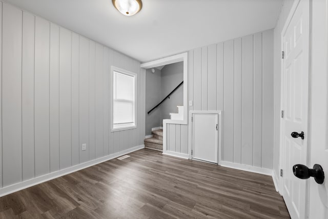 empty room featuring dark wood-style floors, stairway, and baseboards