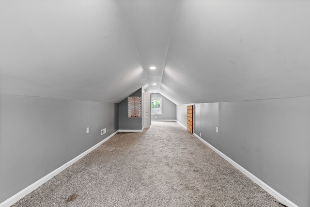 additional living space featuring vaulted ceiling, carpet flooring, and baseboards